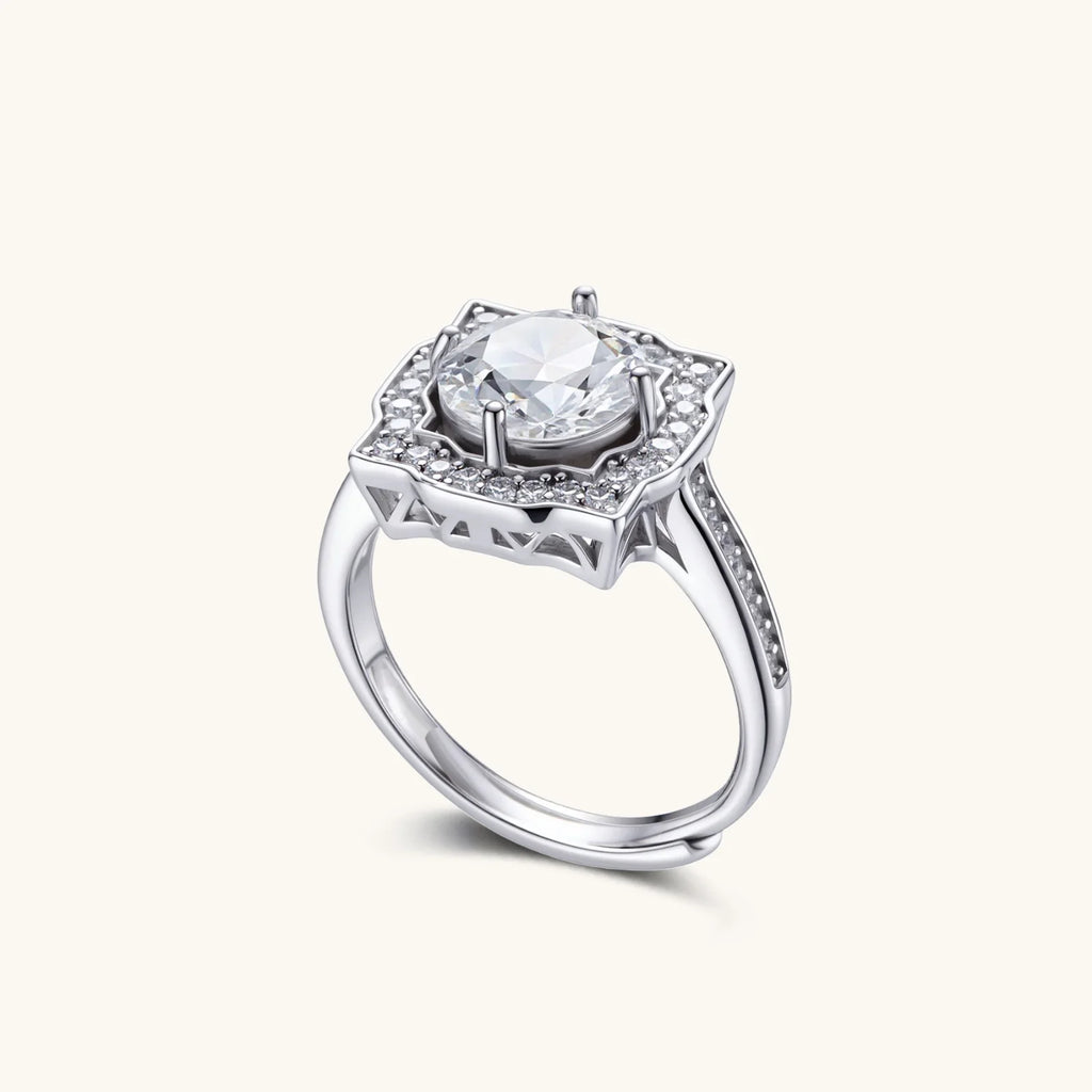 Sterling silver ring with round moissanite center stone in ornate scalloped halo setting on white background.