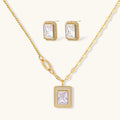 Gold-plated jewelry set with rectangular cubic zirconia stones in pave halo settings on cream background