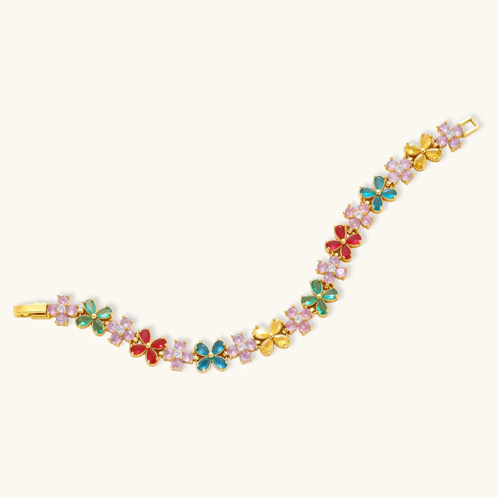 Gold-plated flower necklace, bracelet and drop earrings with multicolor zirconia petals and white round beads on a cream background.