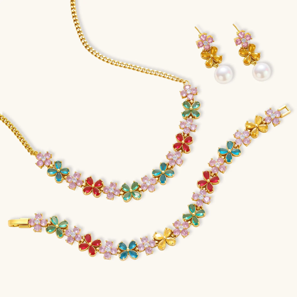 Gold-plated flower necklace, bracelet and drop earrings with multicolor zirconia petals and white round beads on a cream background.