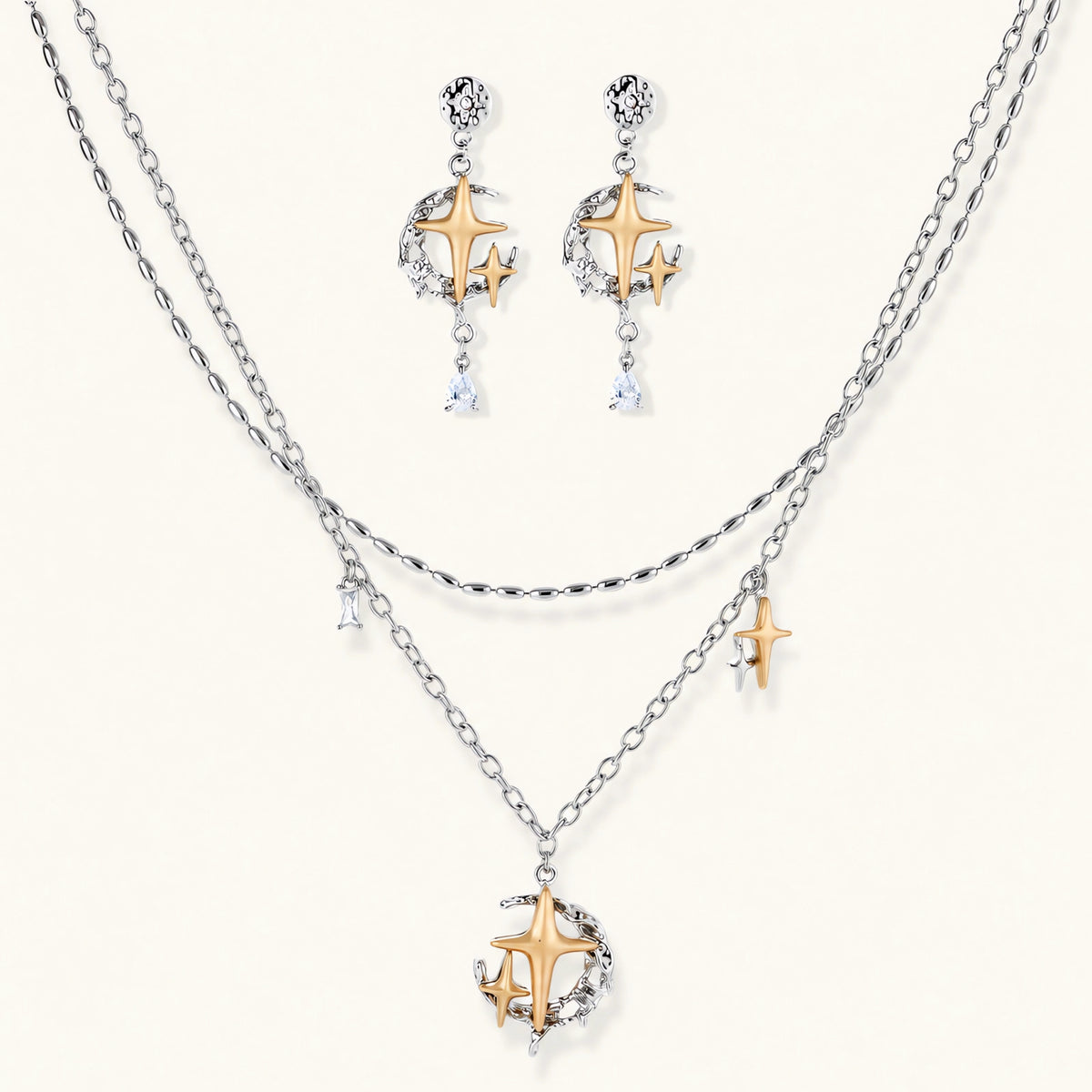 Delicate eco-brass jewelry set featuring gold star and silver moon crescents with clear zirconia crystal drops on cream background