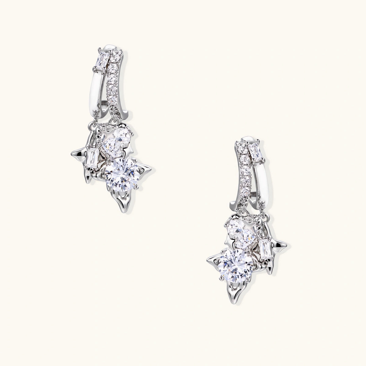 White gold-plated huggie earrings with geometric emerald-cut zirconia clusters in starburst formation on beige background