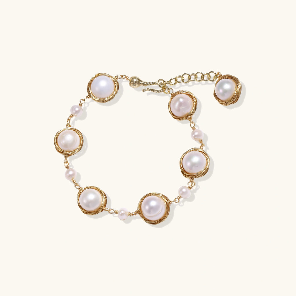 Gold wire-wrapped freshwater pearl bracelet with alternating pearl sizes on cream background, adjustable length
